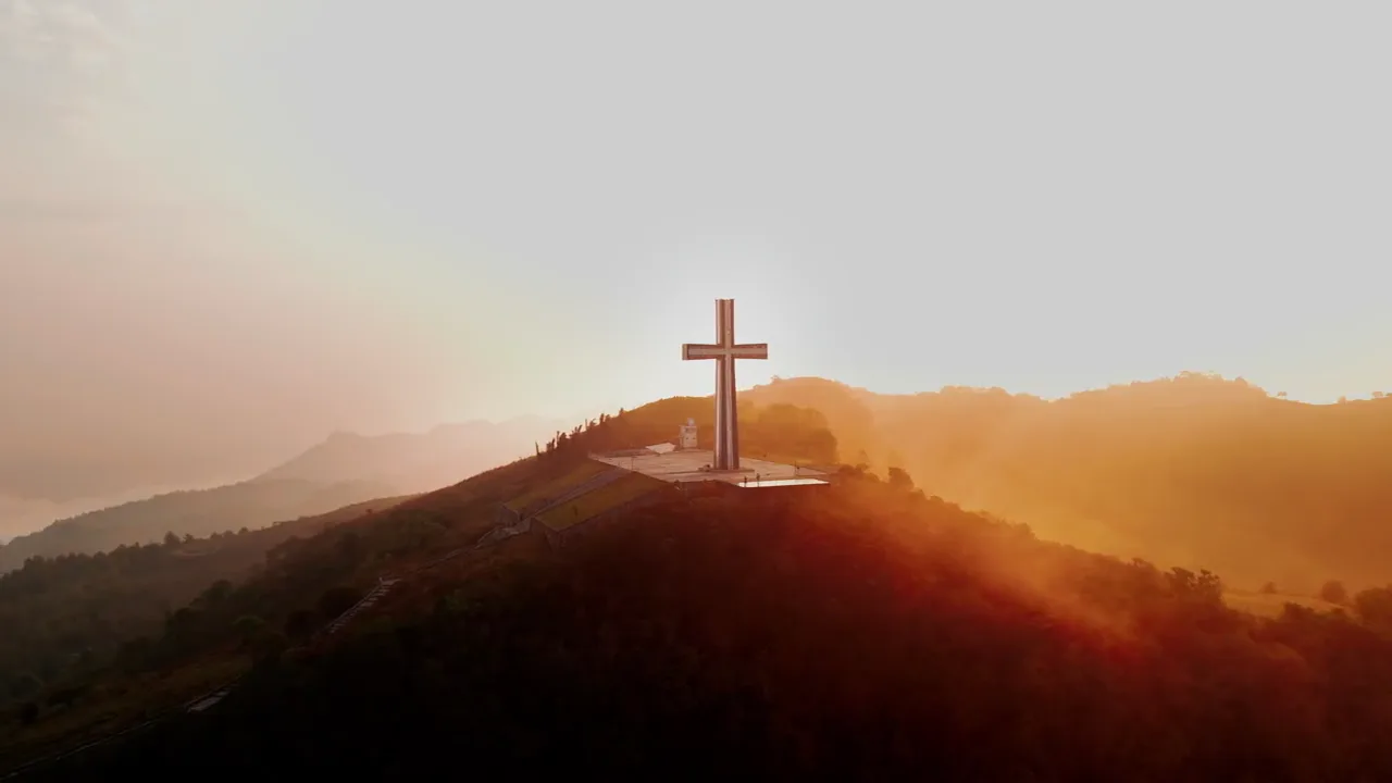 Representative sunrise view of a cross on a mountain